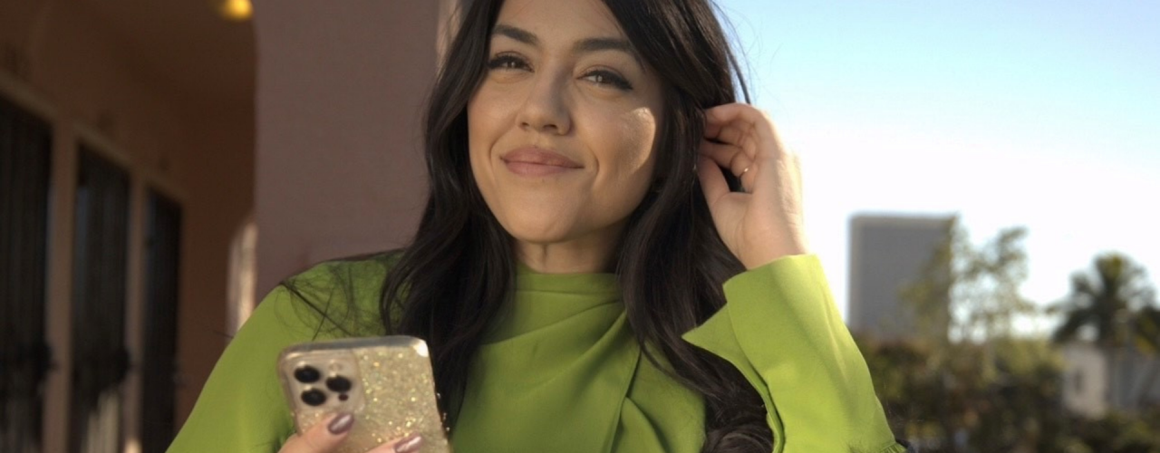 Christen Nino De Guzman está afuera sosteniendo su teléfono celular. 