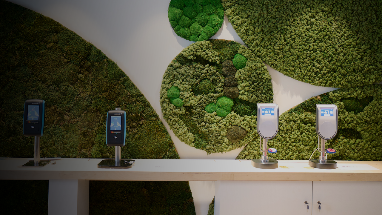 Image of wall with plants and a white desk with four scanners.
