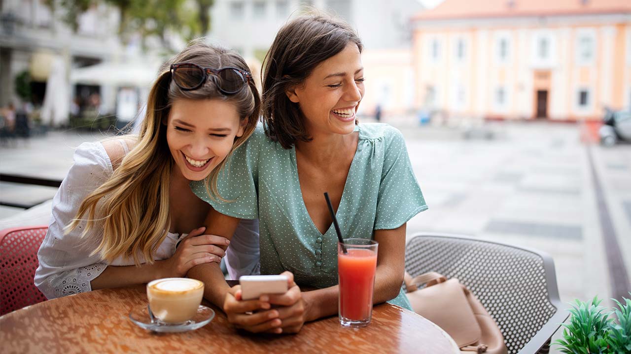 Zwei Freunde lachen in einem Café.