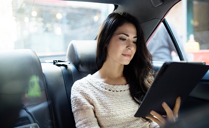 Femme lisant sur sa tablette dans une voiture