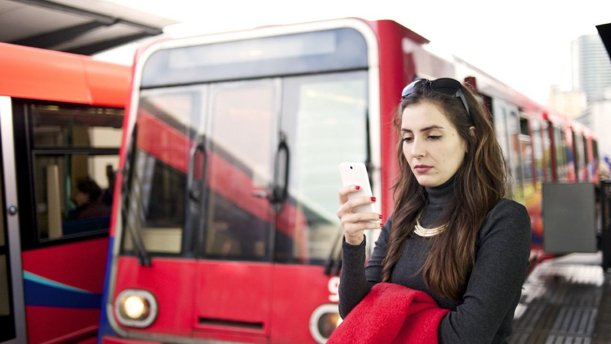 Femme regardant son téléphone à un arrêt de bus.