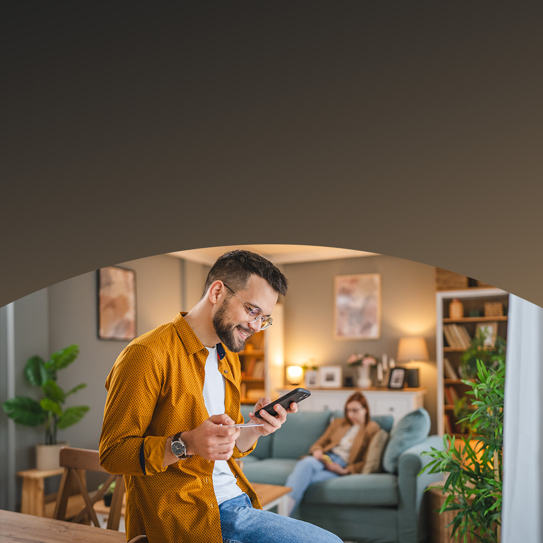 Un homme portant des lunettes effectue un achat par carte depuis son téléphone.