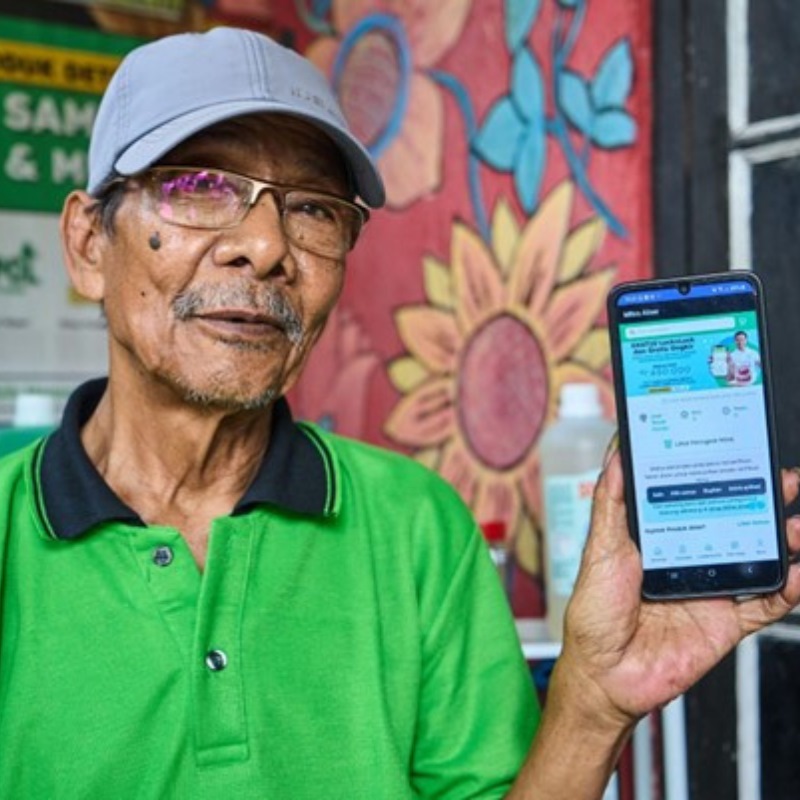 Rozak Ardian holds up a smarthphone open to the Alner app outside a store in Jakarta. 