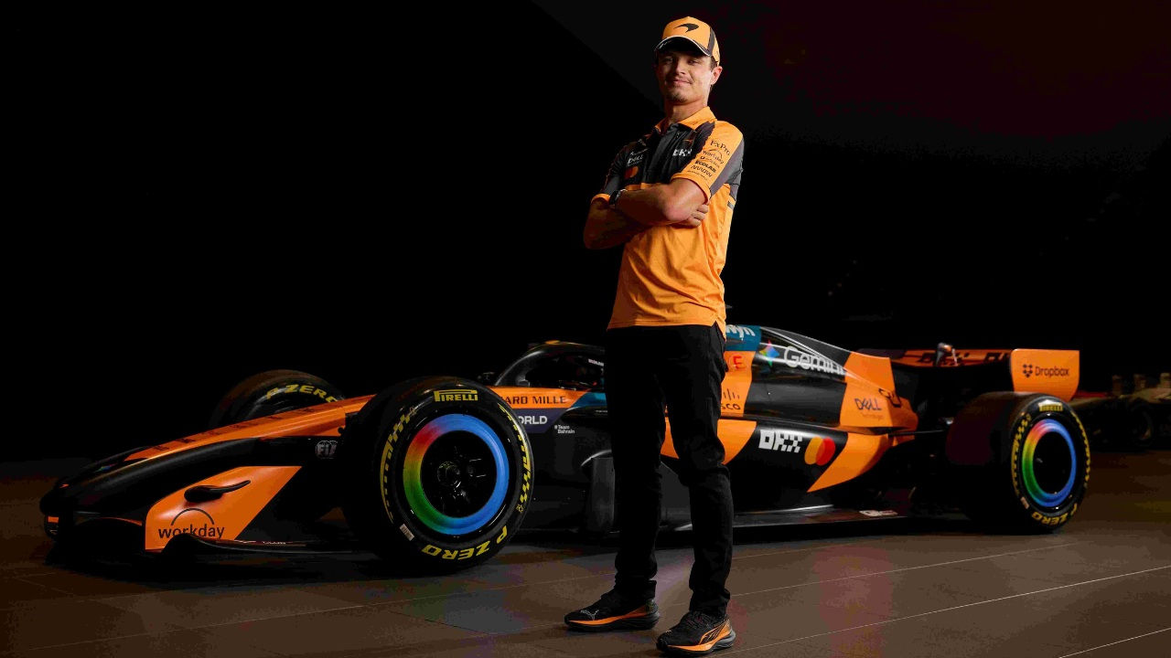 Lando Norris in front of a McLaren Mastercard racing car. 