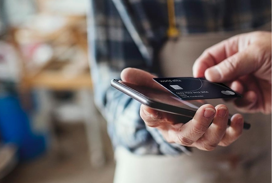 Una persona acerca una tarjeta a un teléfono inteligente. 