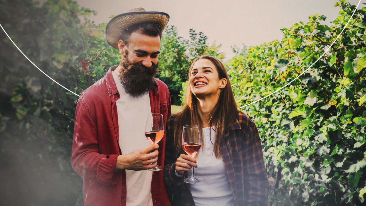 Dos personas conversan en una mesa de restaurante con copas de vino y comida servida.