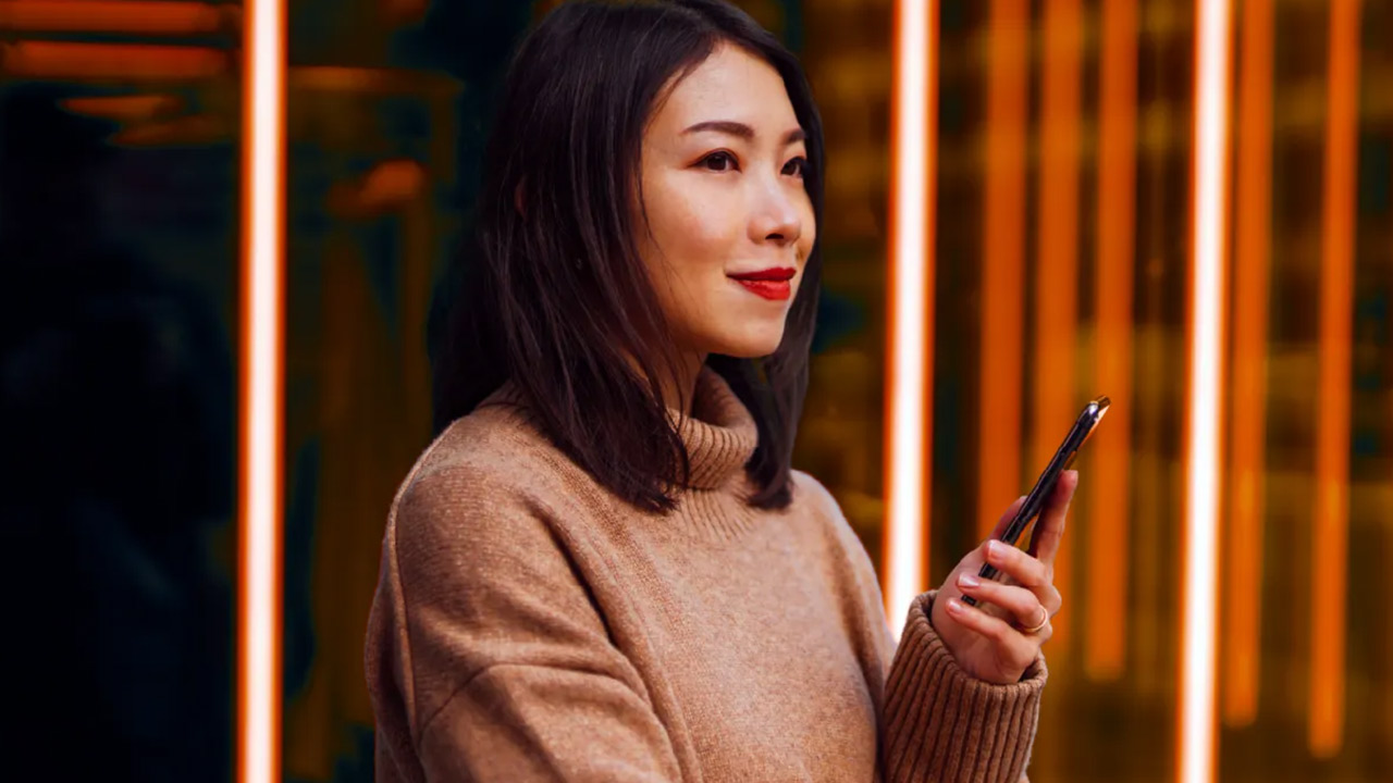 Woman holding a phone in front of glowing vertical lights.