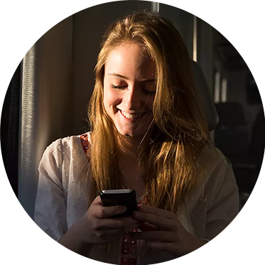 Žena se usmívá a dívá se do telefonu.