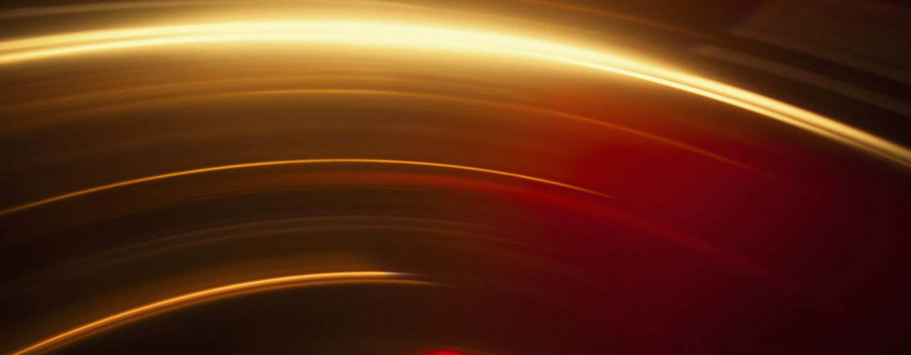 Abstraktes Bild von leuchtend roten und goldenen Lichtspuren vor schwarzem Hintergrund
