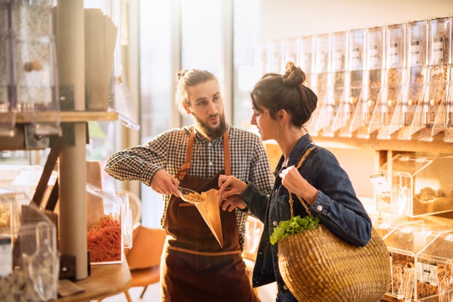 Smuk ung kvinde handler i en butik med bulkfødevarer.
