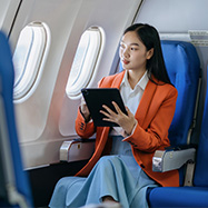 en ung forretningskvinde, der arbejder på en tablet, mens hun sidder i et fly.