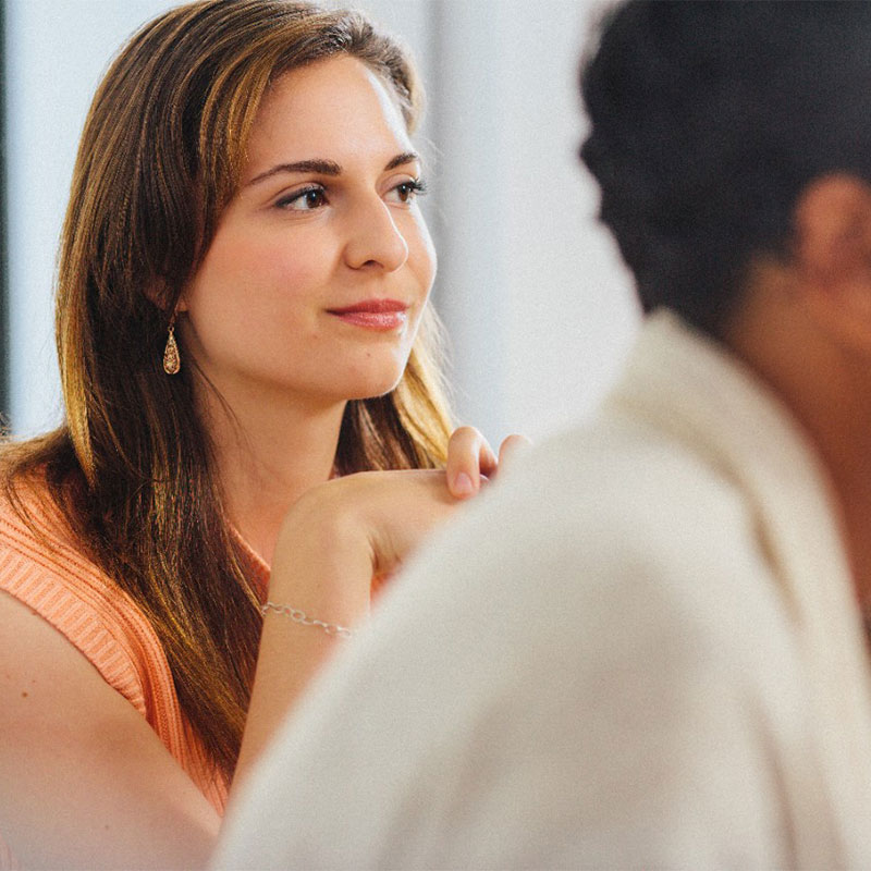 Et portræt af en kvinde, der sidder og lytter opmærksomt.