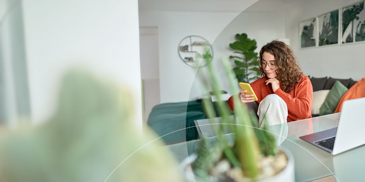 En ung smilende kvinde med briller, der holder en smartphone.