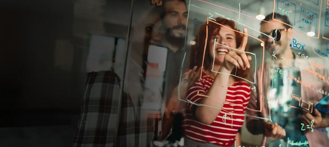 A person smiling and pointing at a chart on a screen during a presentation or meeting.