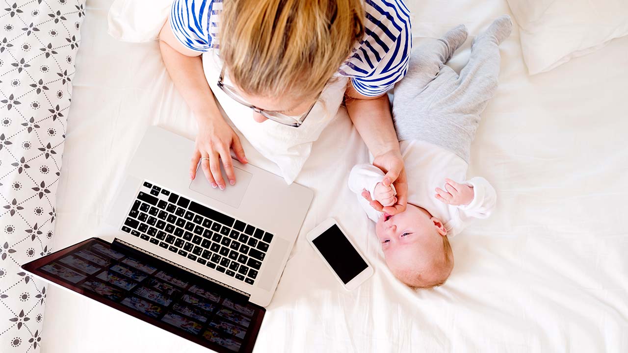 Mor og barn ved siden af en laptop og en mobiltelefon.