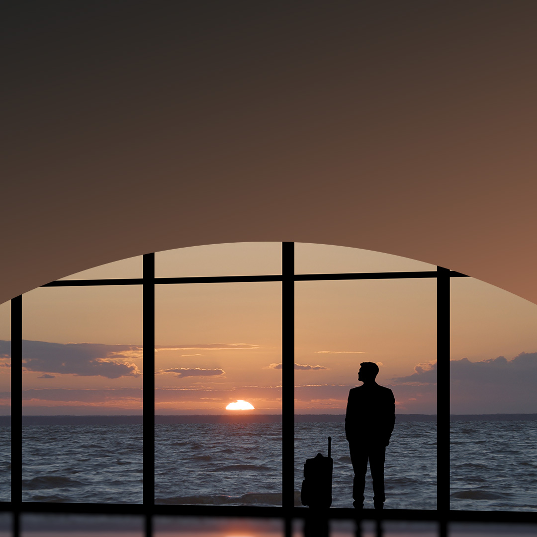 Man with a suitcase standing near a panoramic window.