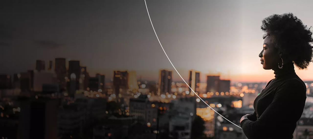 Mujer al aire libre en la cima de una colina con vistas a la ciudad al atardecer