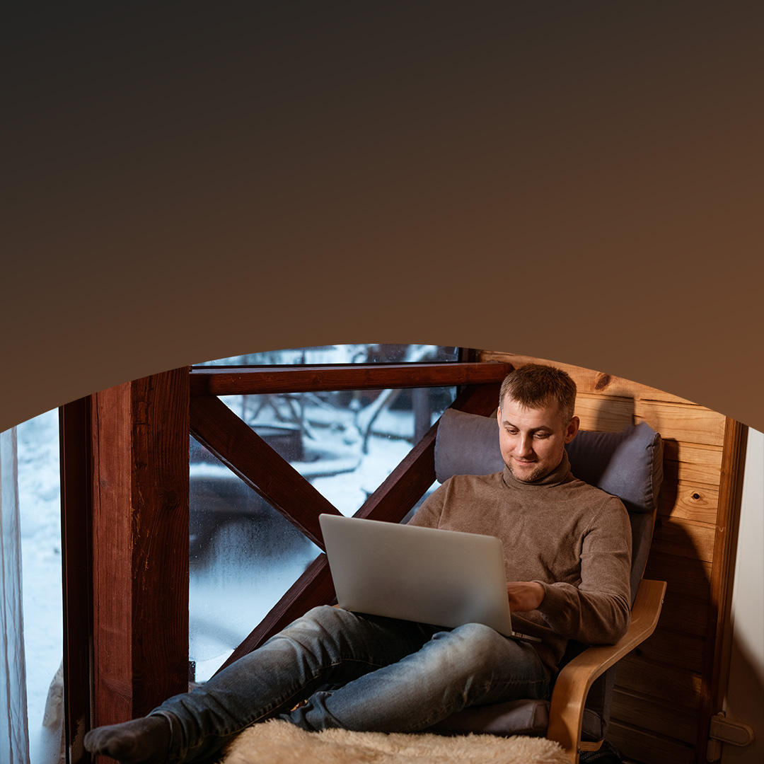 Man sitting in chair looking at laptop.