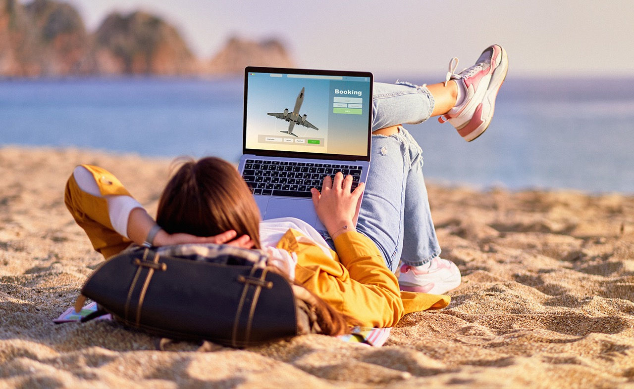 Woman on beach navigating laptop.