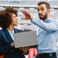 Businesswoman uses laptop computer as she talks to colleague.