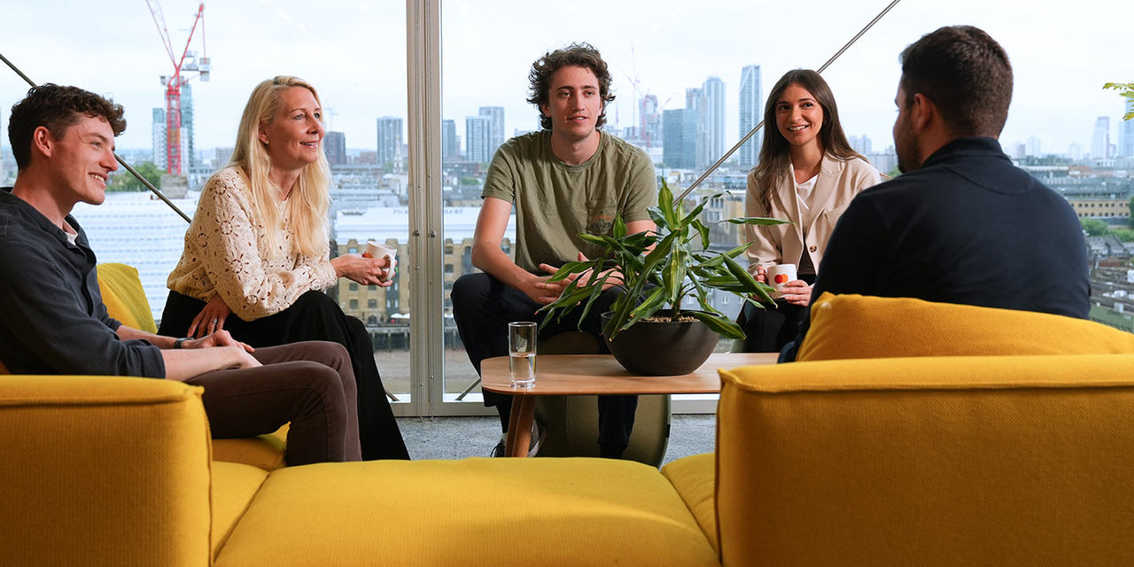 Group meeting in a lounge area with yellow chairs.