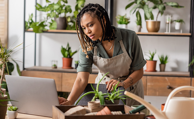 Woman standing over laptop checking screen.