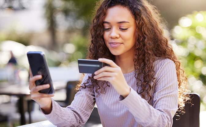 Woman holding phone and credit card.