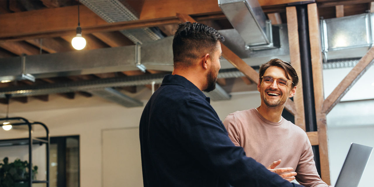 Two coworkers laughing while working at the office