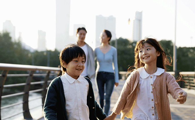 Two smiling siblings walking in front of their parents