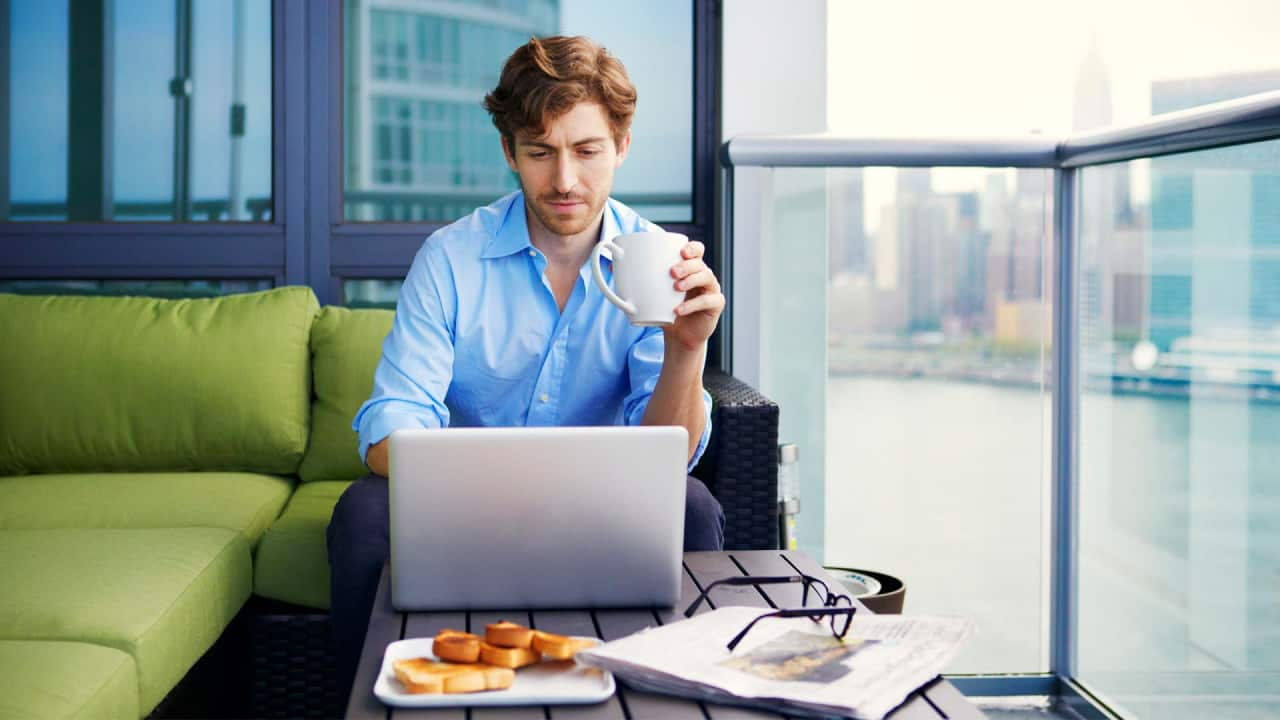man drinking tea looking into laptop