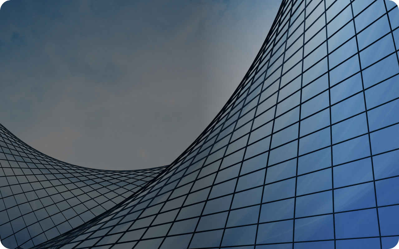 A blue building featuring a sleek, curved glass wall reflecting sunlight.