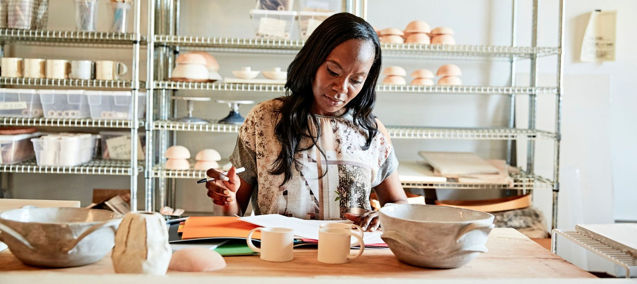 A woman looks over paperwork in her pottery studio. 