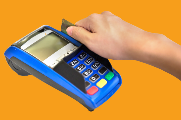 A swipe POS machine against an orange background with a hand swiping a card. 
