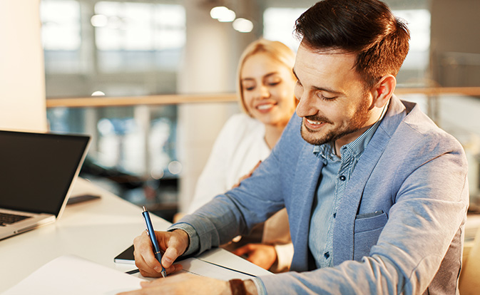 Un homme et une femme sont assis à une table, collaborant sur un ordinateur portable.