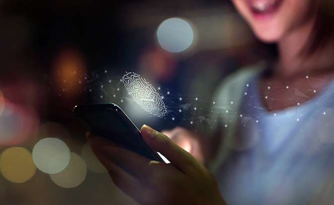 Une femme scanne son empreinte digitale sur un smartphone pour authentifier en toute sécurité son identité grâce à une vérification biométrique.
