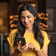 Une femme indienne souriante utilisant un smartphone.