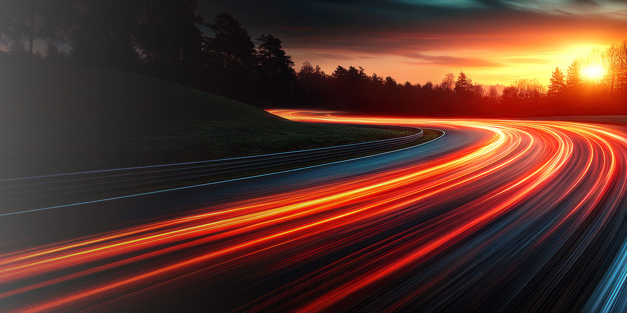 Route au coucher du soleil avec des traînées claires illustrant le mouvement.