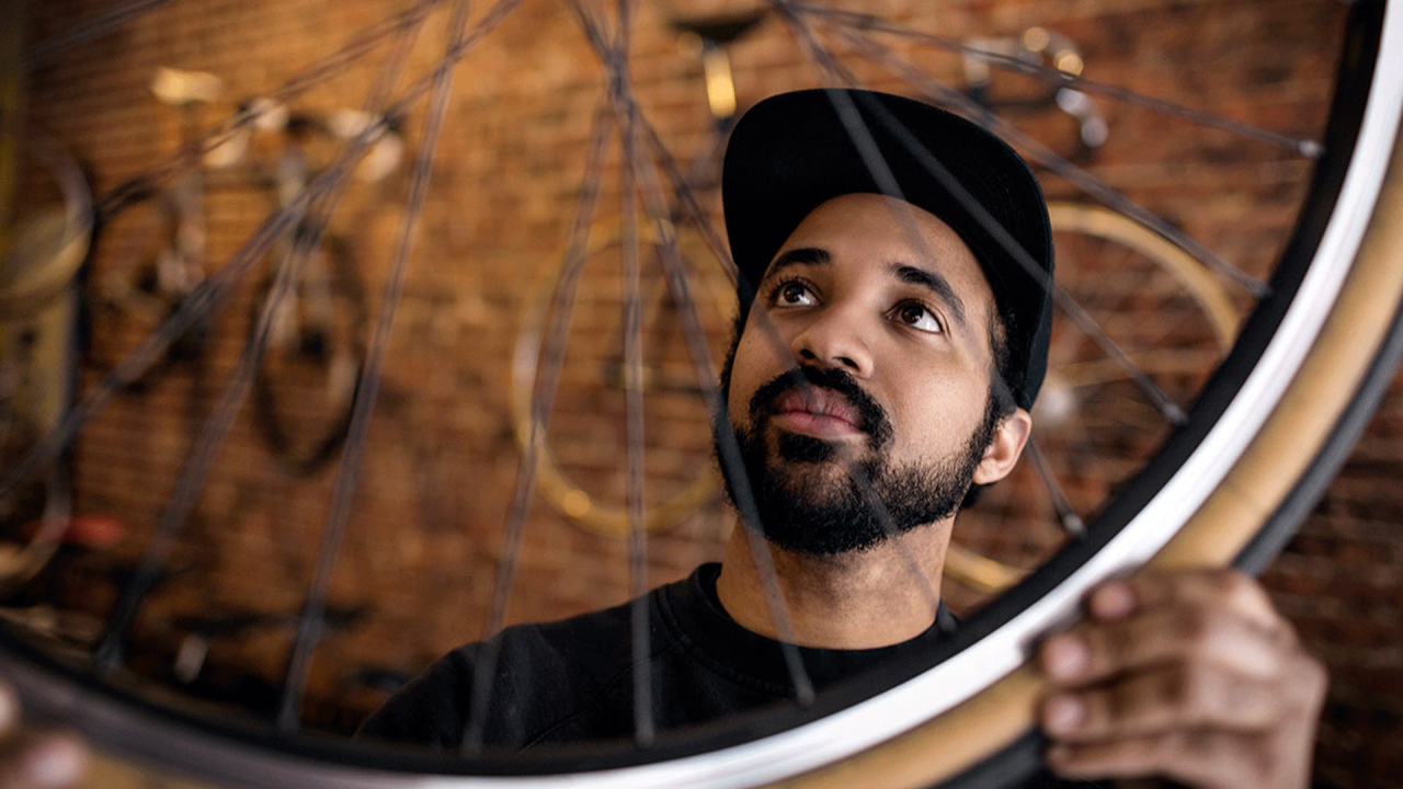 Homme inspectant une roue de vélo.