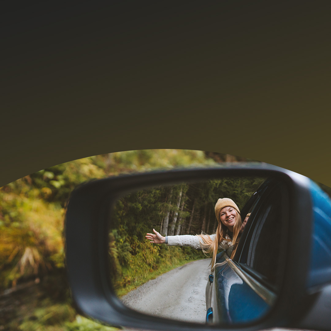 Woman waving hand out of car window.