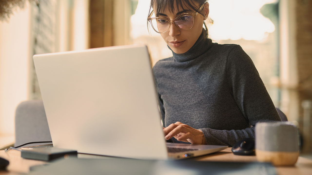 portrait of skilled young female developer in eyeglasses concentrating on screen 