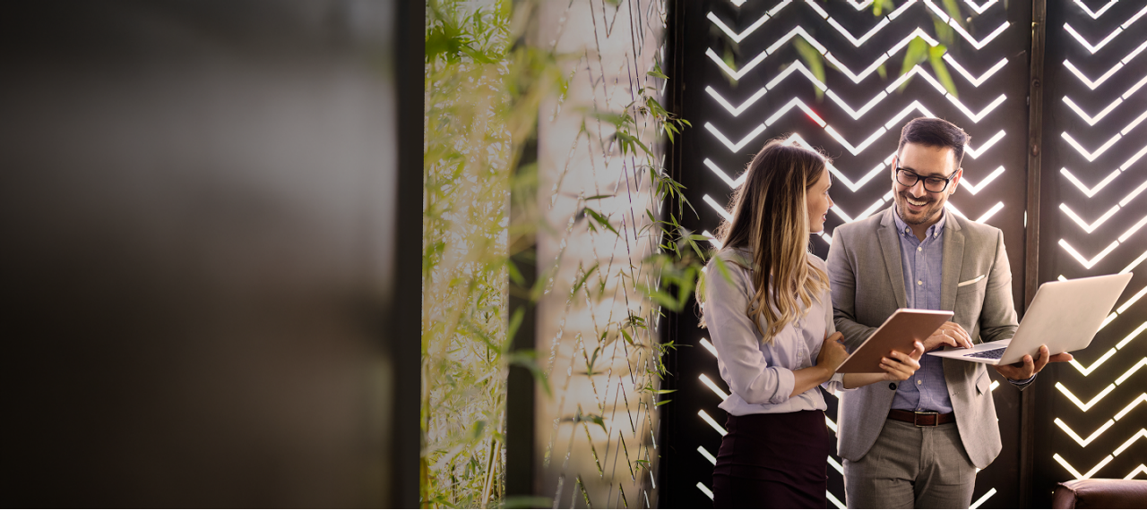 A man and woman standing in front of a laptop