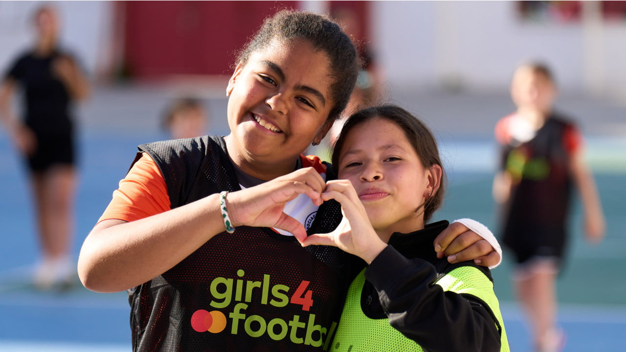 two smiling girls giving heart