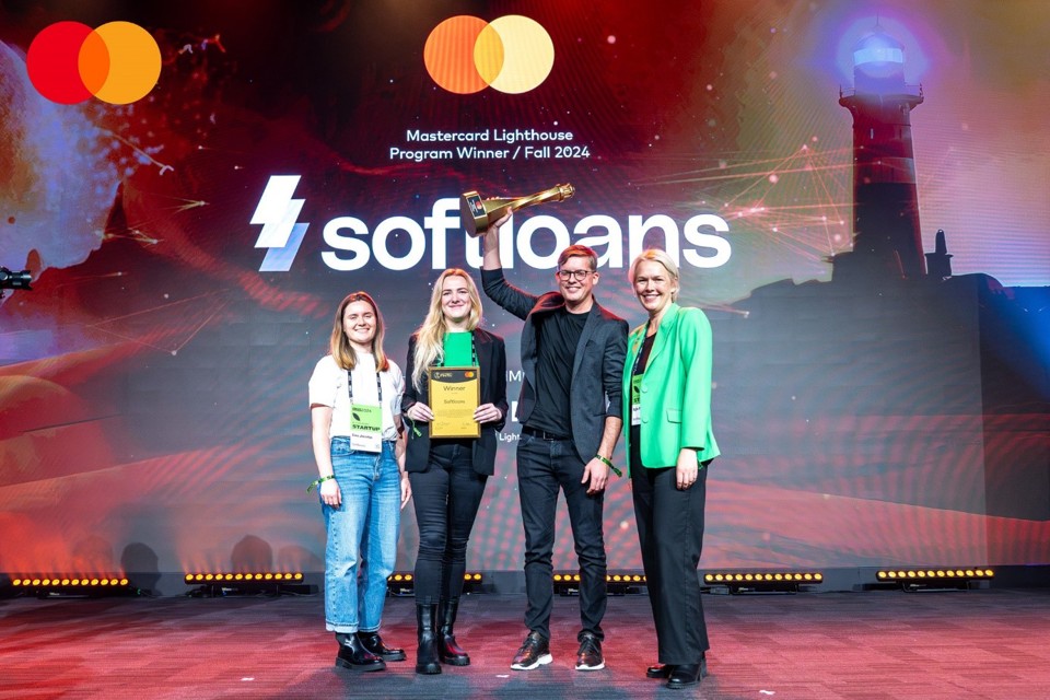 A group of Mastercard lighthouse winners on stage with one of them holding up a trophy