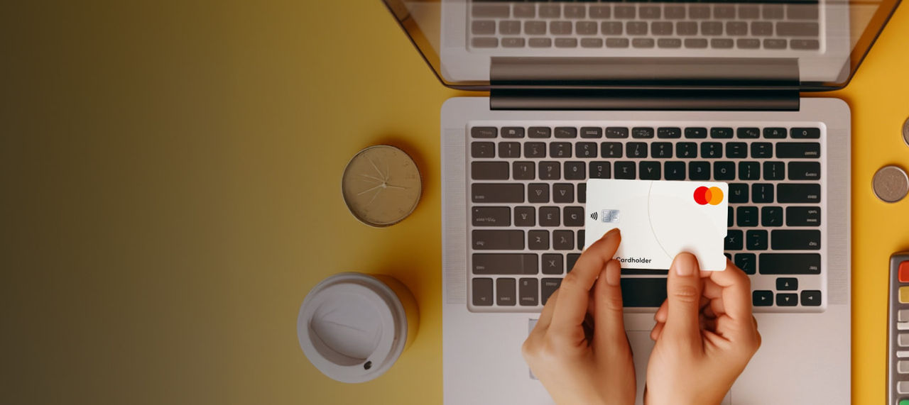 hands holding card over laptop