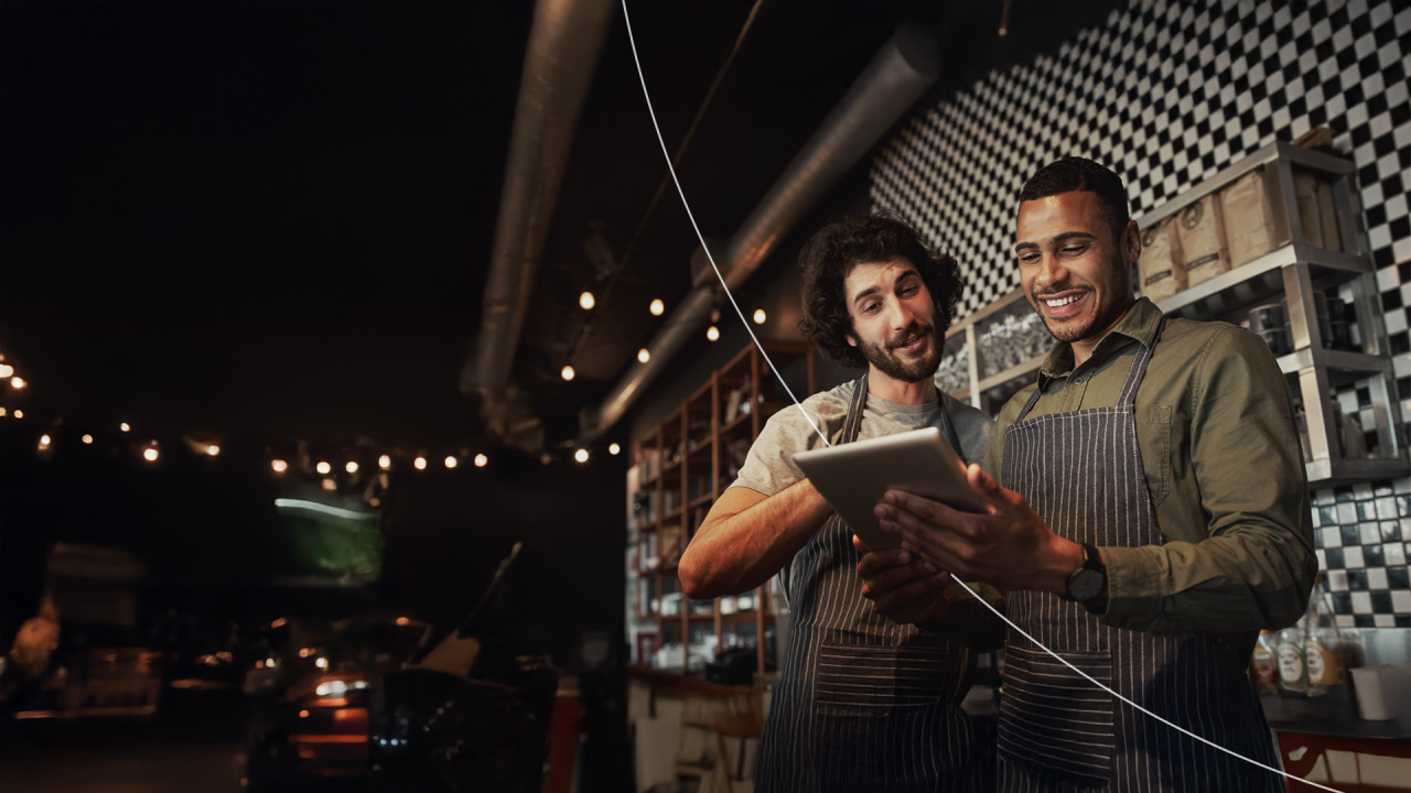 Two business owners smiling while scrolling on a tablet