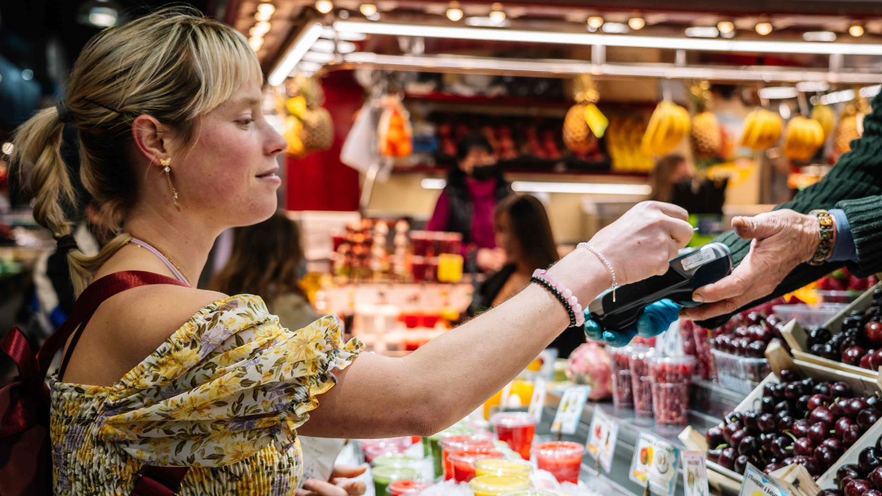 A woman pays at a Barcelona market using her card. 