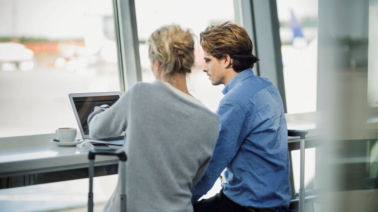 Two colleagues look at a laptop together. 