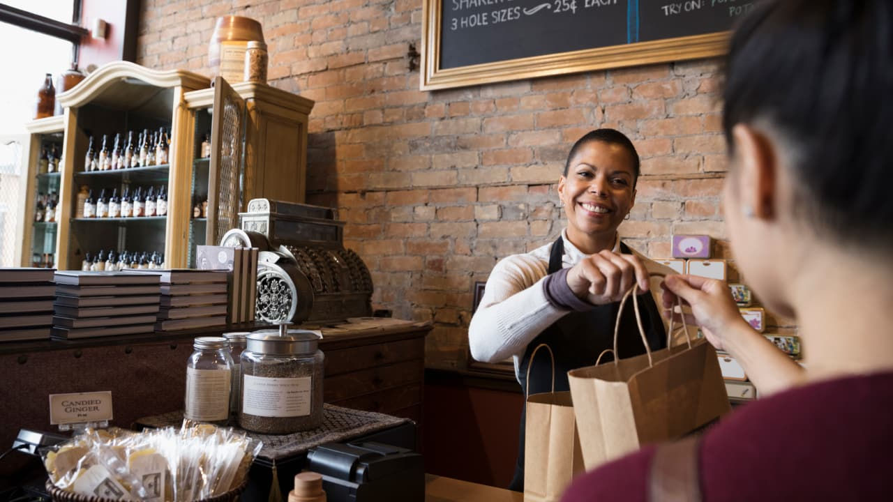 smiling woman giving package in a shop