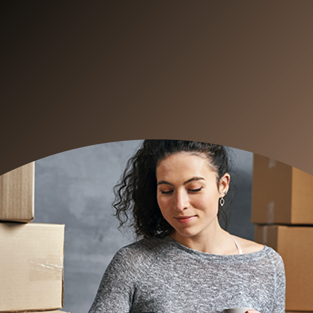 Small business owner surrounded by shipping boxes paying with phone. 