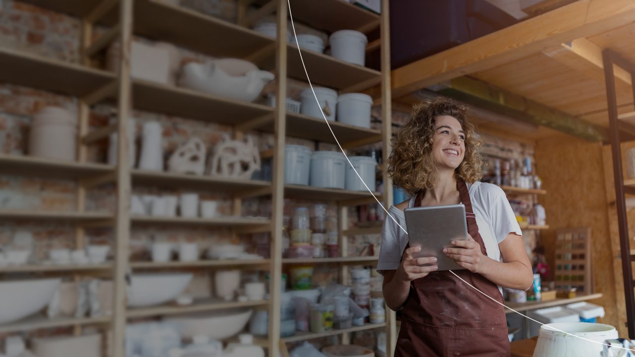 Smiling small business owner holding iPad. 